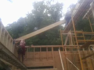 Carpenter raising a rafter beam on a new second story frame in Halifax