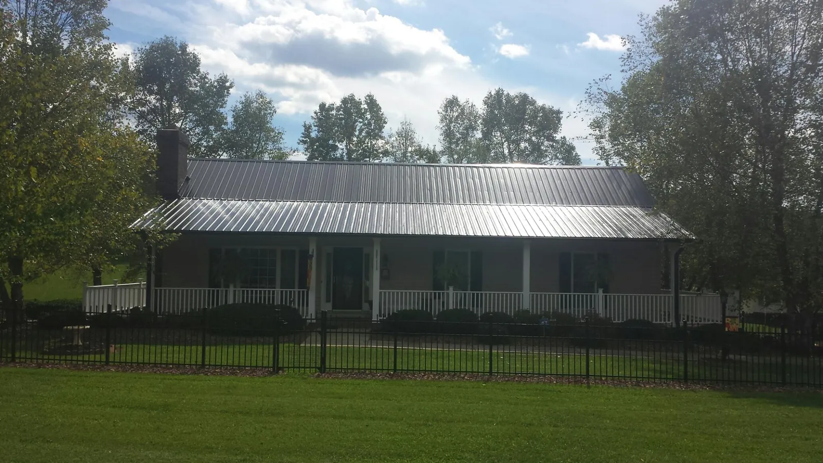 Gray metal roof on a brick ranch with a full width front porch — Gutter Guard Installation work by our crew in Halifax