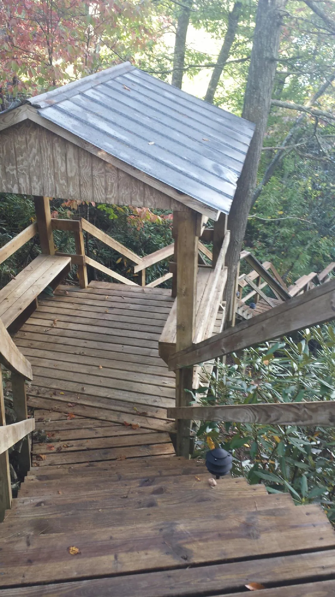 Metal roofed shelter over wooden steps on a wooded walkway — Skylight Repair & Installation work by our crew in Halifax