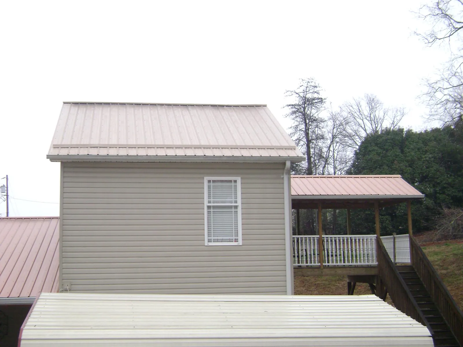 Tan metal roofs on a two story addition and attached porch, from a Roof Replacement job in Halifax